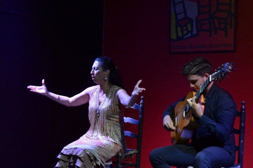 A person playing a guitar and another person gesturing. 3