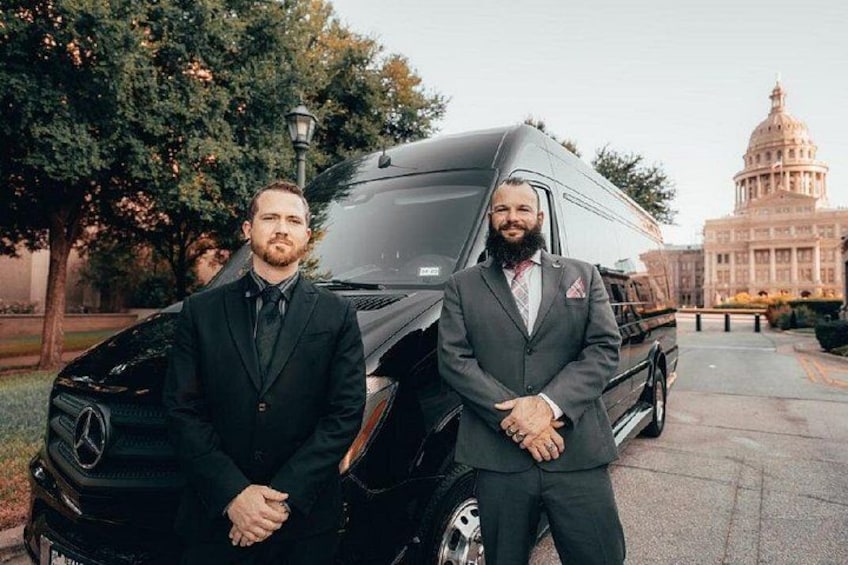 Dos hombres con traje de negocios de pie junto a una camper van negra Mercedes-Benz. 4