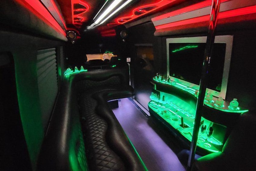 Una habitación con poca luz, luces de neón verdes y rojas, un banco curvo y una vitrina con objetos. 5