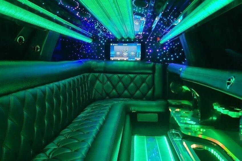 Un interior lujoso con iluminación ambiental verde, una pantalla digital y un área de estar confortable. 2