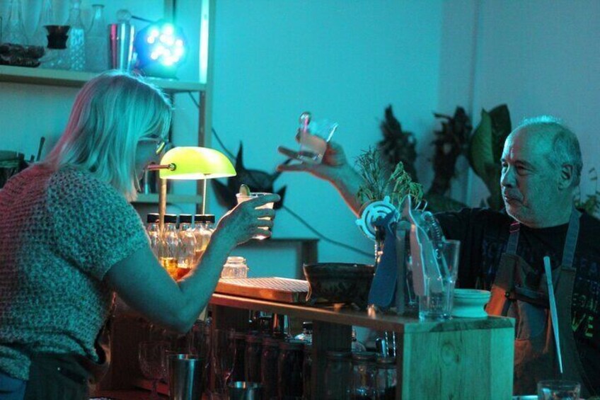 A person holding a glass, a bar counter with bottles, and a lamp. 3