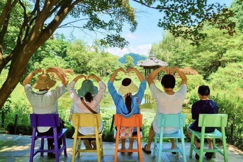 Four people sitting on colorful chairs, forming a heart shape with their hands. 5