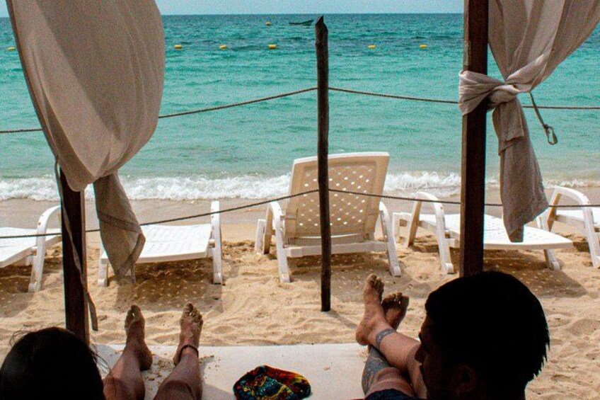 Une plage avec des chaises longues blanches et une personne allongée sur le sable. 2