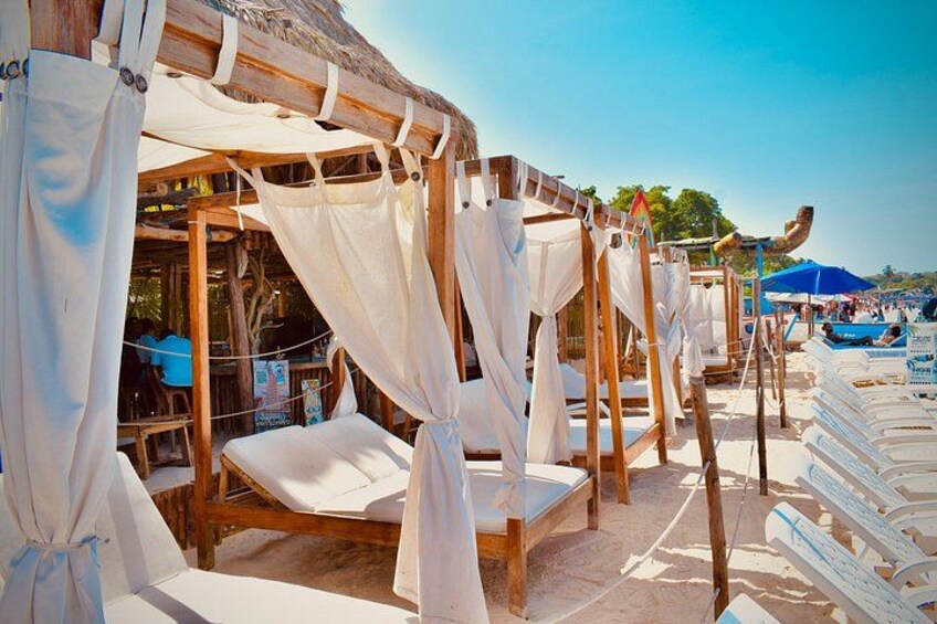 Wooden cabanas with white canopies, a beach setting, and a clear sky. 2