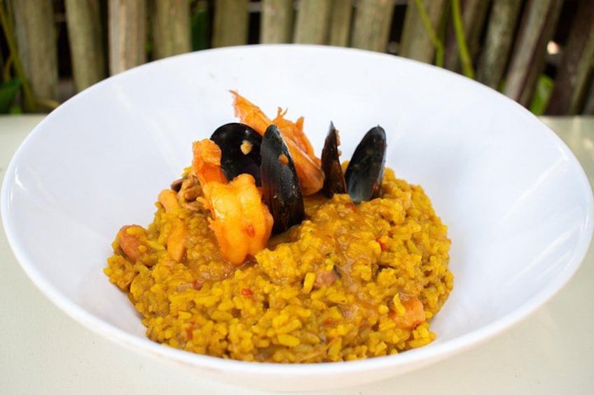A white plate of paella with seafood and vegetables. 5