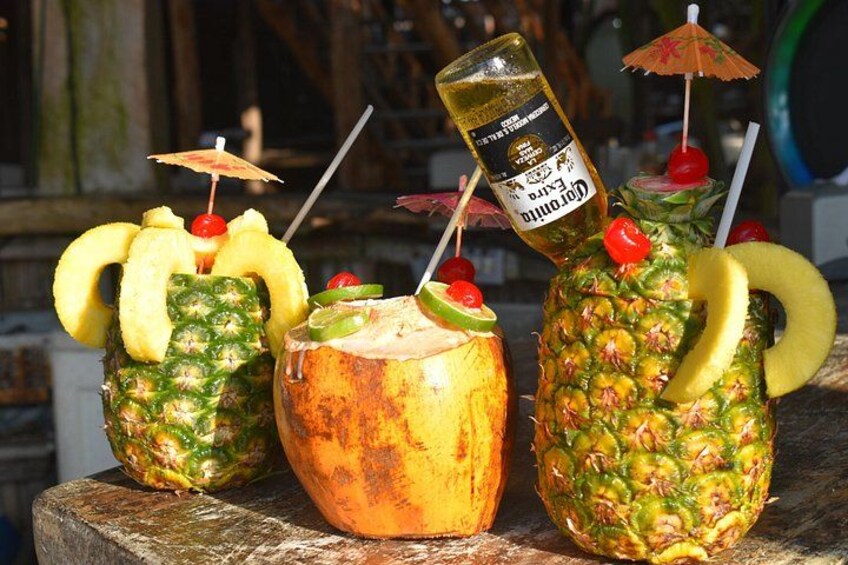 Three tropical drinks in pineapple shells with straws and umbrellas. 3