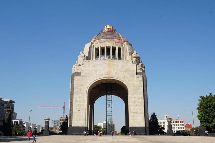 Une grande arche en pierre surmontée d’un dôme, entourée de bâtiments et s’ouvrant sur un ciel dégagé. 3