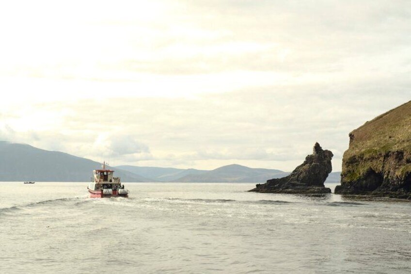A boat on calm water with a rocky outcrop on the right. 4