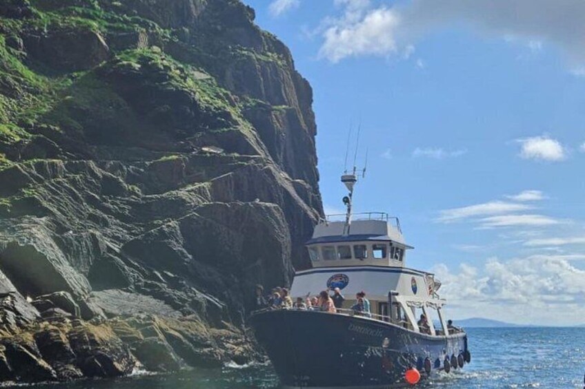 A boat near a rocky cliff with people on board. 5
