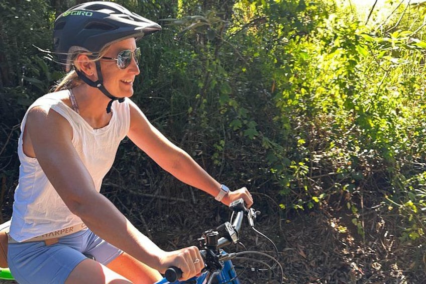 A person riding a bicycle in a natural setting with dense foliage. 1