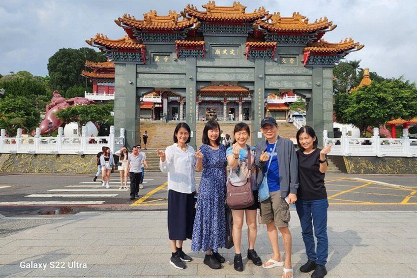 A group of people in front of a traditional Chinese gate with ornate architecture. 2