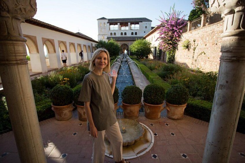 A person standing in a courtyard with a fountain, surrounded by potted plants and historic architecture. 4