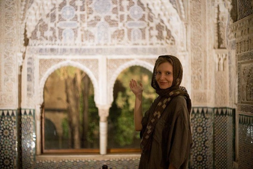 A person standing in a historic building with intricate tile work and arches. 4