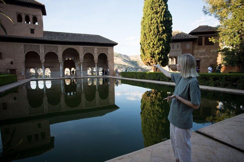 A person standing by a reflective pool with a historic building in the background. 3