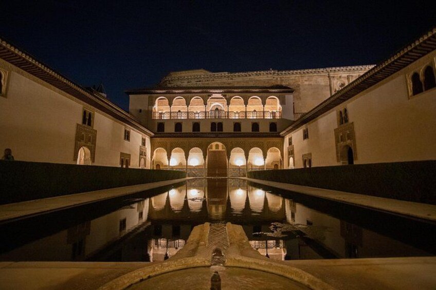 A nighttime view of a historic building with a reflective pool in the foreground. 2