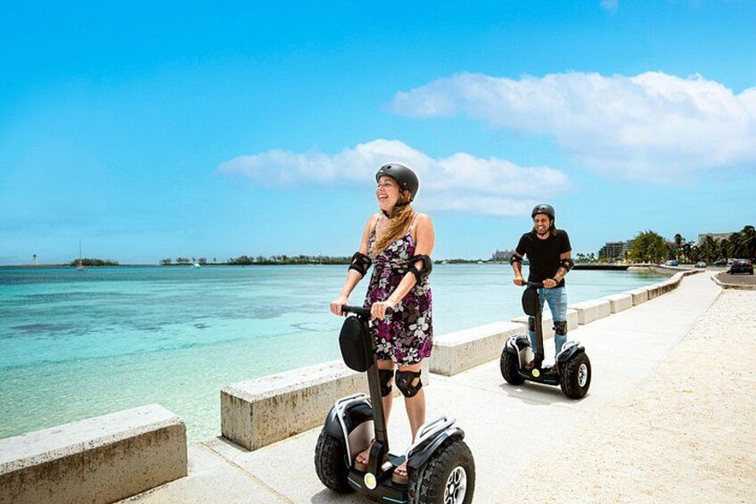 Two people on segways near a waterfront with clear water and a distant shoreline. 3