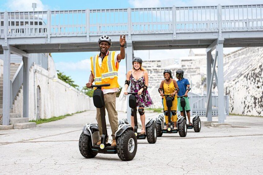 Personas montando Segways sobre un puente con muros de piedra y cielo despejado. 3