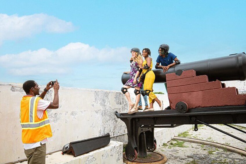 A cannon on a rooftop, a person taking a photo, and three people observing. 4