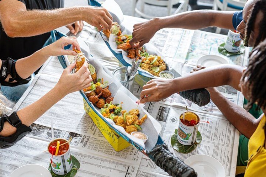 Personas comiendo en una mesa con recipientes de comida y bebidas. 2