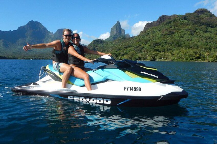 Two people on a jet ski with a mountainous landscape in the background. 1