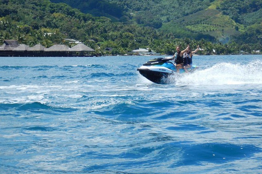 A person jet-skiing on a body of water with a tropical landscape in the background. 2