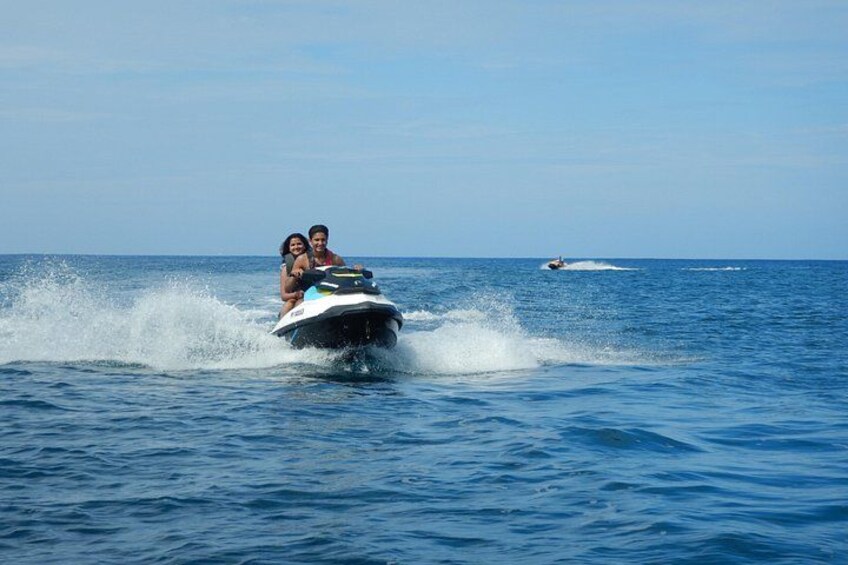Un jet ski con due persone, schizzi d'acqua e un altro jet ski sullo sfondo. 2