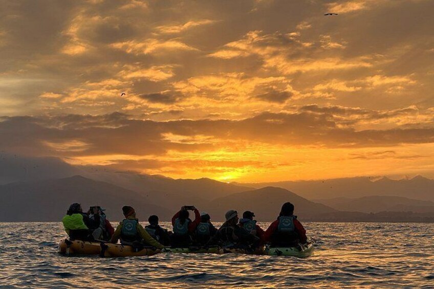 Un grupo de personas en una balsa en el agua, con montañas al fondo durante el atardecer. 5