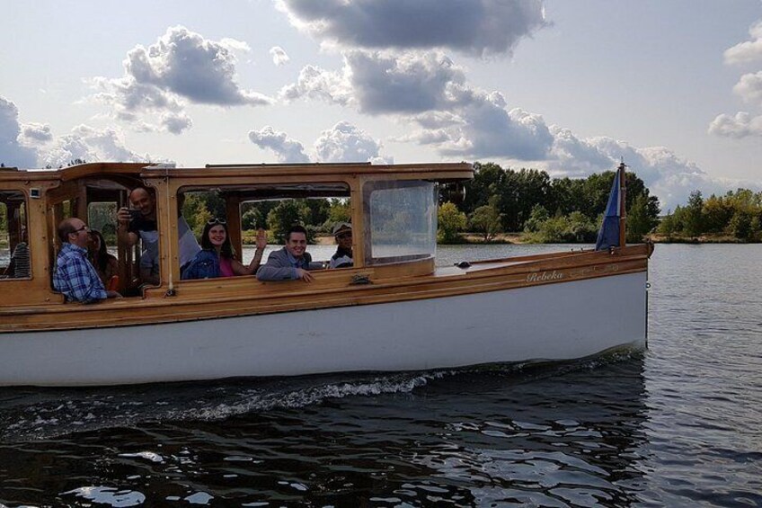 A boat with passengers on a calm lake, surrounded by trees and a cloudy sky. 3