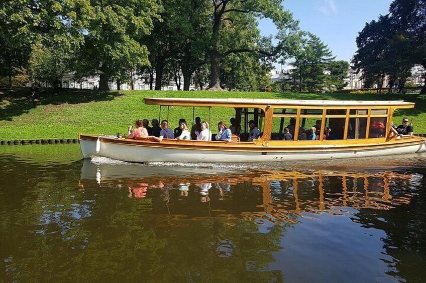 A boat with passengers on a calm river surrounded by trees. 4