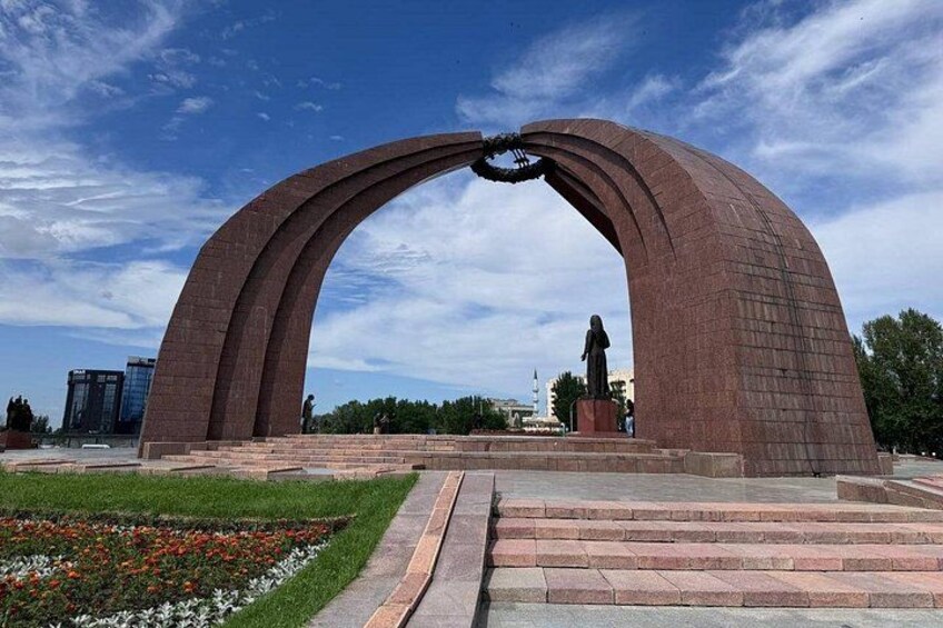 A large arched monument with a statue in the center, surrounded by a landscaped area with steps leading up to it. 5