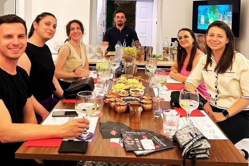 Un groupe de personnes est assis autour d’une table en bois, devant de la nourriture, des boissons et des magazines. 3