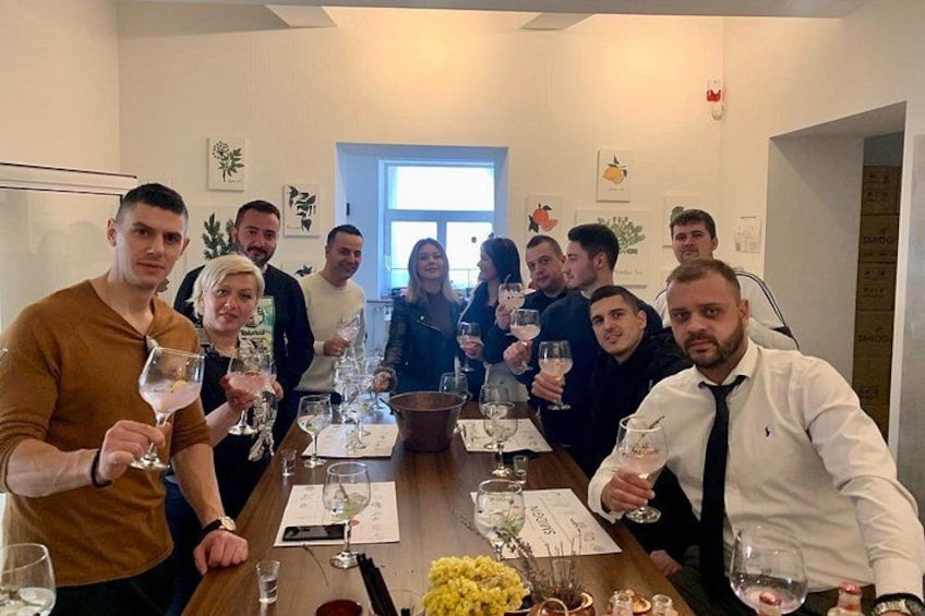 Un groupe de personnes est assis autour d’une table, devant des verres à vin, un menu et un vase rempli de fleurs. 2
