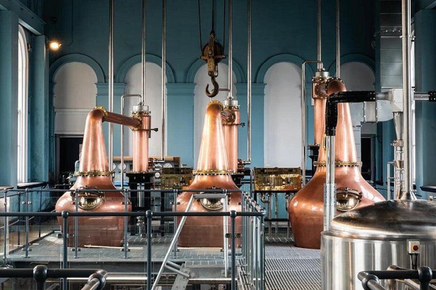 Koperen distillatiekolommen in een distilleerderij met een blauw interieur. 3