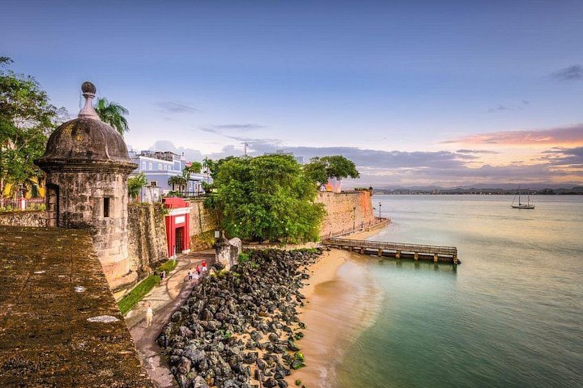 A coastal fortification with a red door, a small dome structure, and a wooden pier extending into calm waters. 4