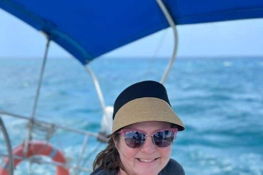 A person on a boat with a blue canopy, ocean in the background. 5