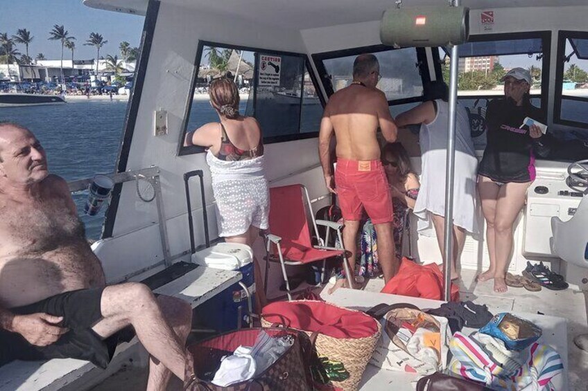 A boat with people on deck, a beach with palm trees, and a body of water. 1