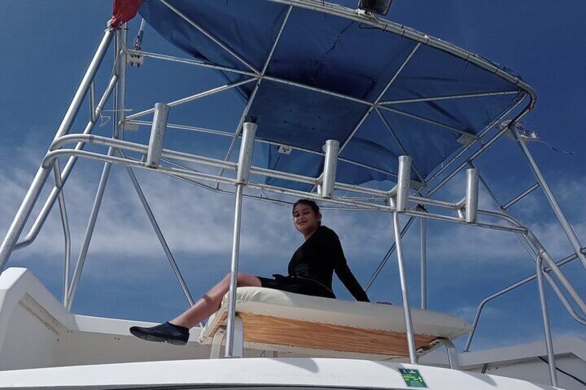 A person sitting on a boat with a blue canopy. 4