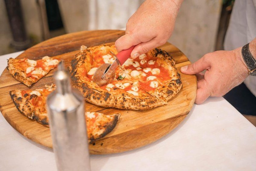 Une personne qui découpe une pizza sur une planche en bois. 3