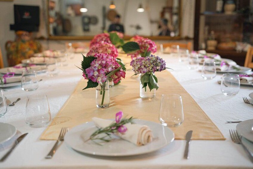 A dining table with vases of flowers, plates, and cutlery. 2