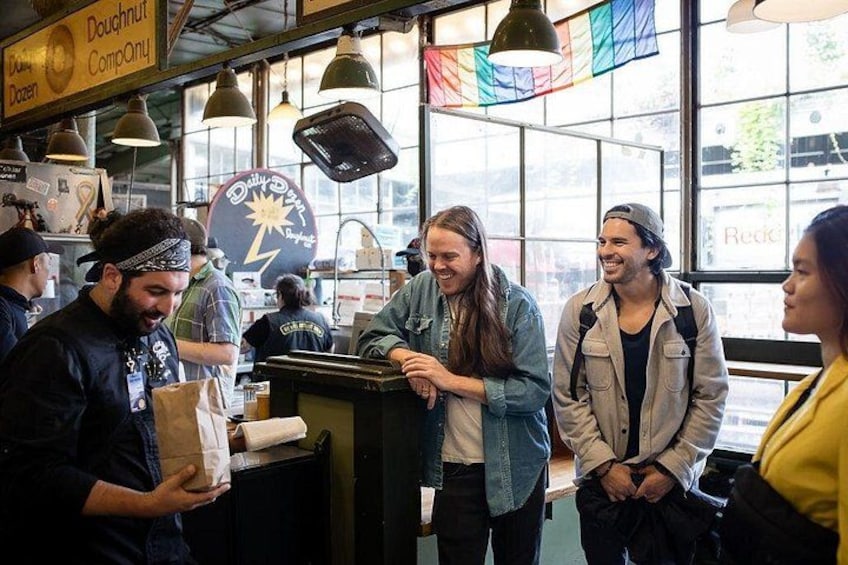 A bakery with a doughnut display and people interacting. 5
