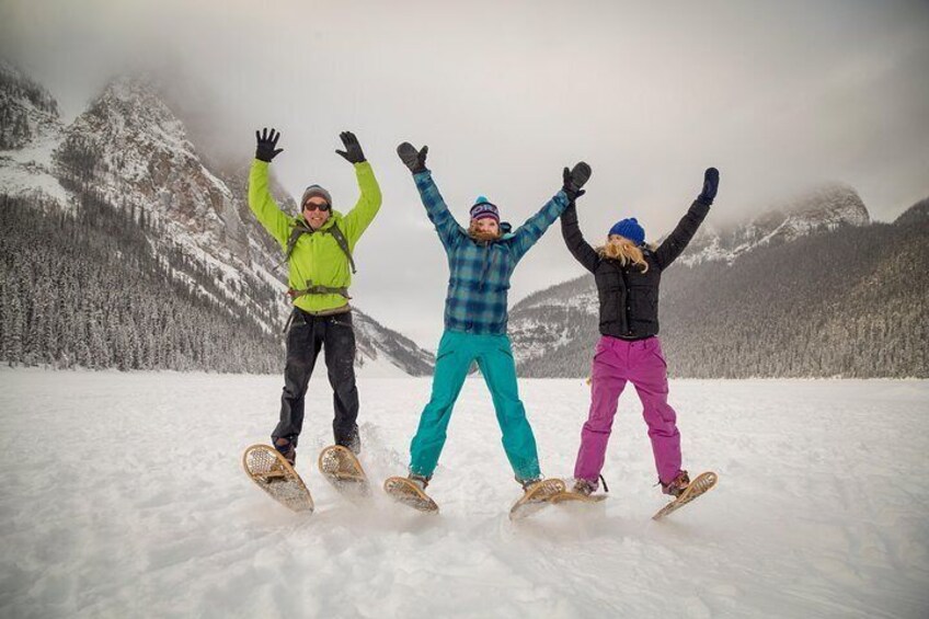 Three people snowboarding on a snowy mountain with trees in the background. 1