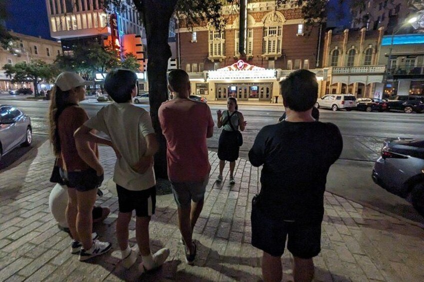Un groupe de personnes marchant sur un trottoir, de nuit. 1