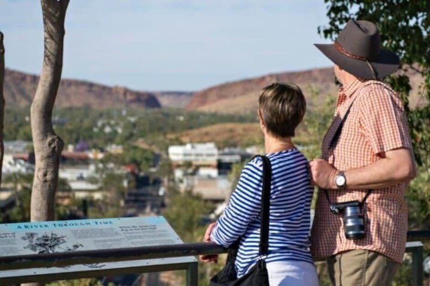 Un hombre y un niño de pie junto a un cartel con vistas a un valle y edificios. 2