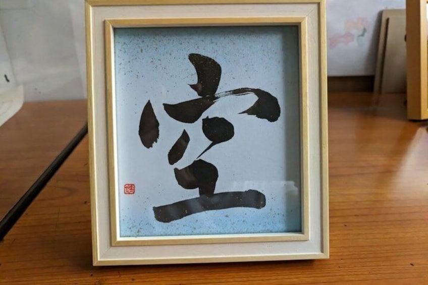 A framed calligraphy artwork on a wooden surface. 3