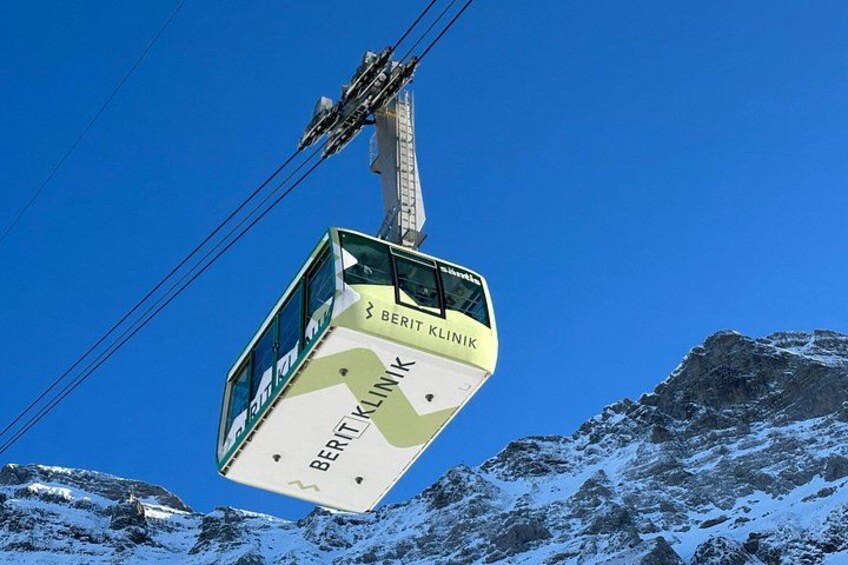 A cable car labeled 'BERITZ KLINIK' suspended between mountains. 4
