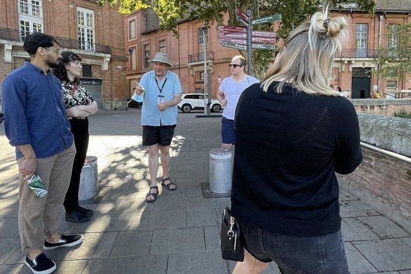 Un grupo de personas sobre una acera, un edificio de ladrillo y una señal de calle. 2