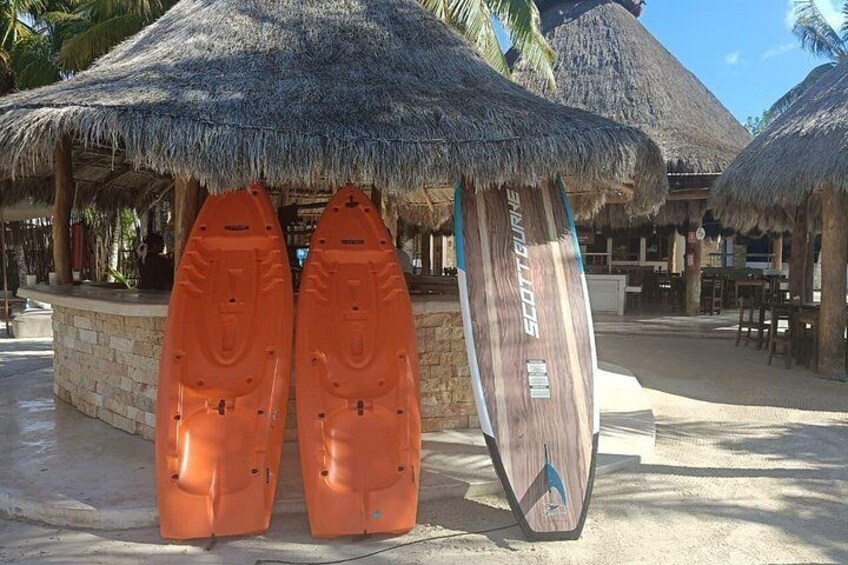 Two orange kayaks and a wooden paddleboard under a thatched roof structure. 4