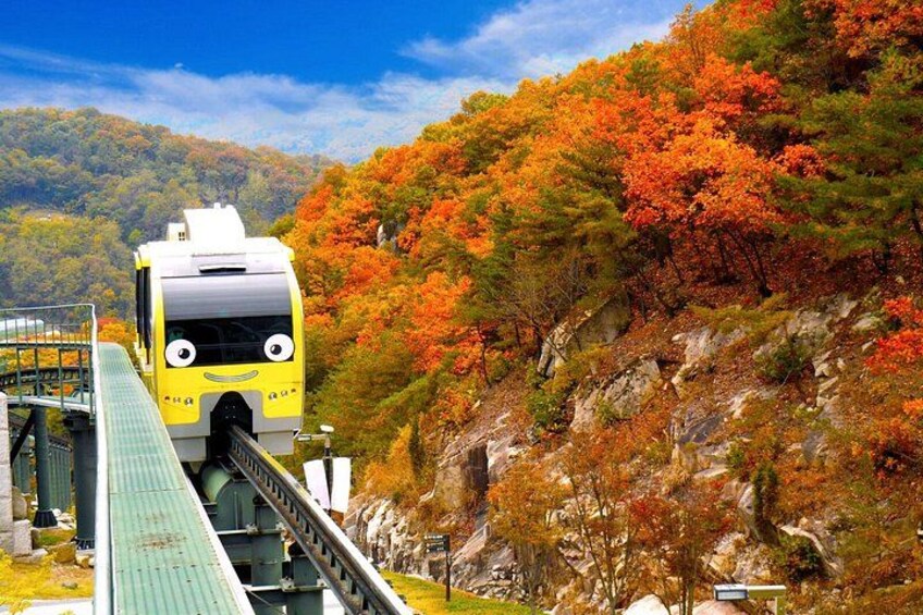 A yellow train with a smiling face on a bridge, surrounded by autumn-colored trees. 3