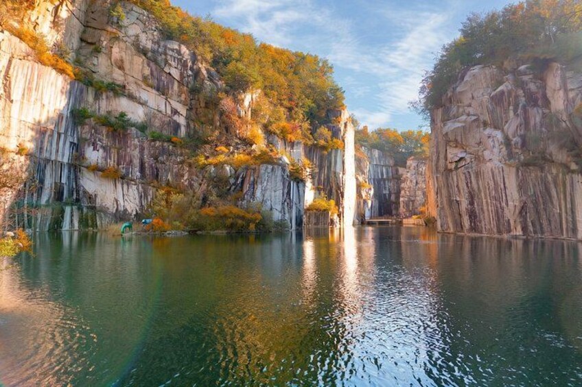 A calm lake surrounded by rocky cliffs with autumn foliage. 5