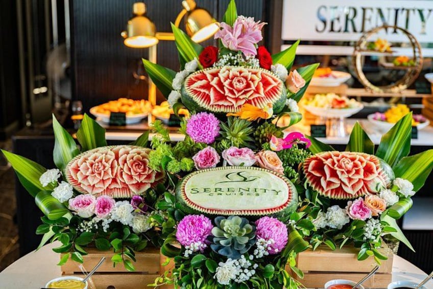 Een tafel met een bloemenstuk en een taart waarop 'Serenity' staat. 5